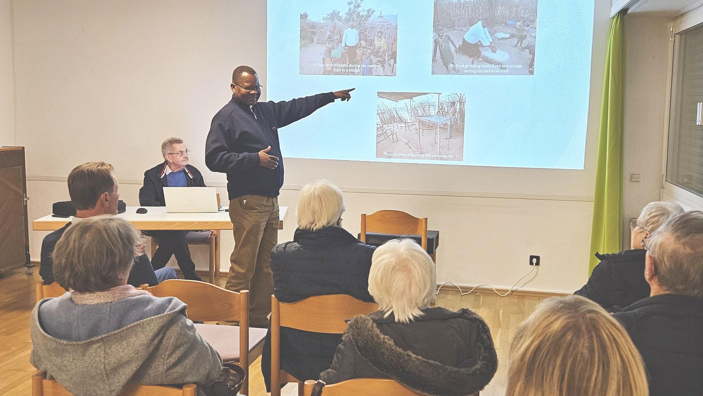Generalvikar Ngole zeigt bei seinem Vortrag Bilder auf einer Leinwand.